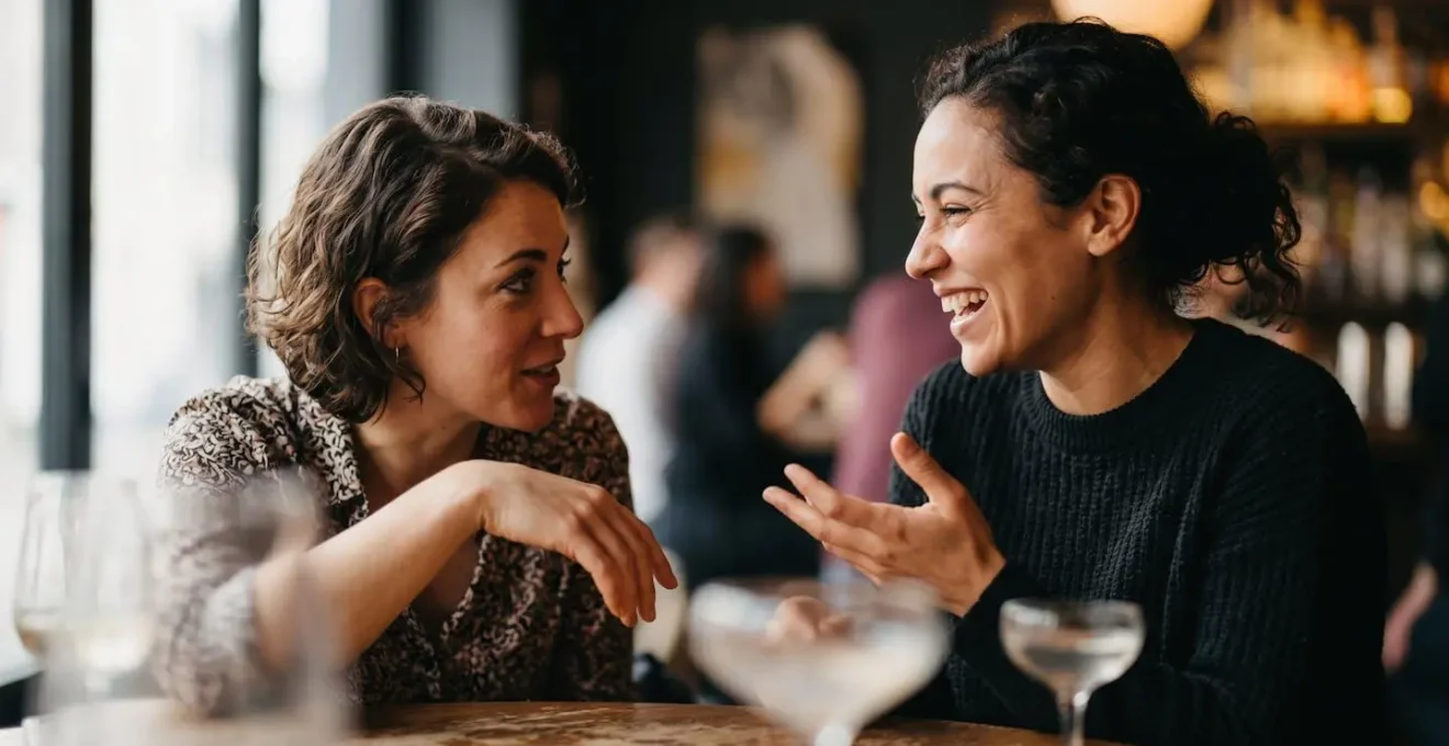 Close-up of two people in genuine conversation with natural eye contact, leaning in with interest at a bar.